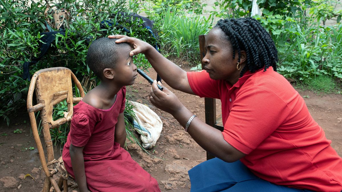 Eine Frau leuchtet im Freien mit einer kleinen Taschenlampe in die Augen eines kleinen Mädchens.