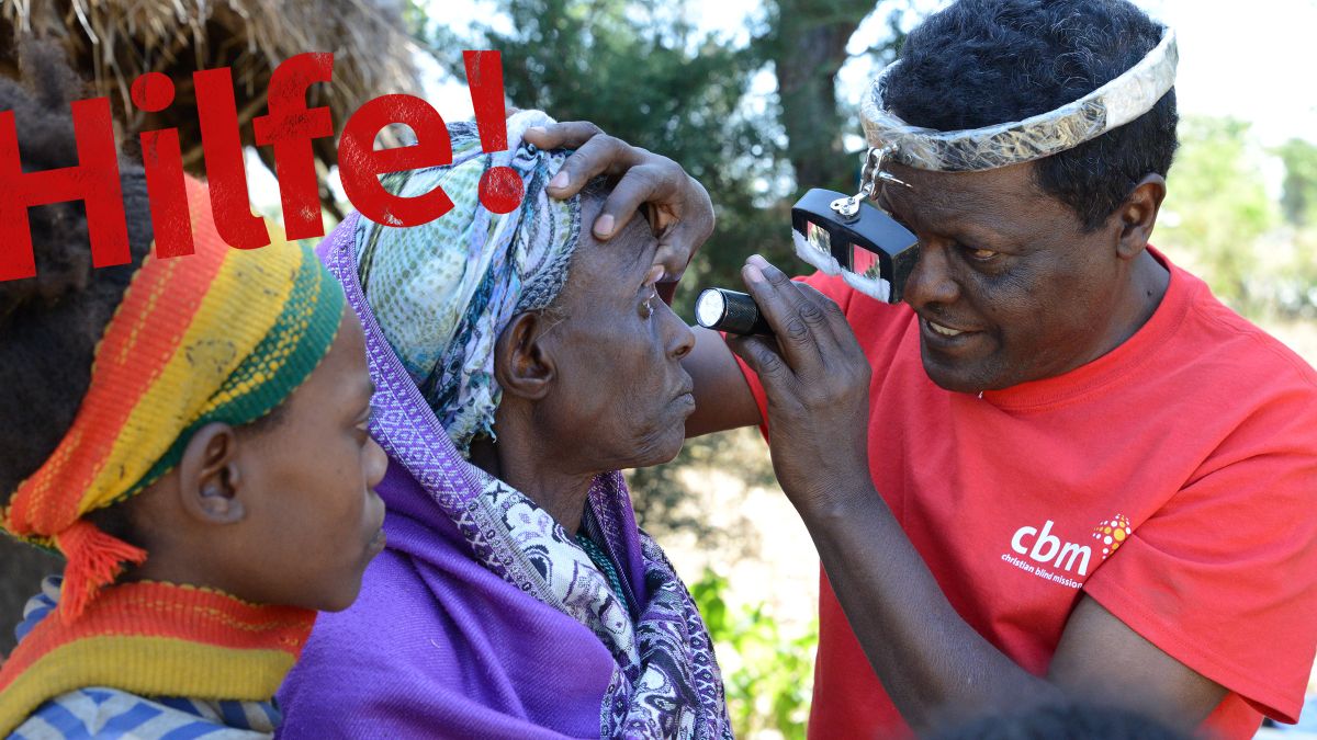 Ein Mann im T-Shirt mit CBM-Logo leuchtet mit einer Taschenlampe zur Untersuchung in die Augen einer Frau.