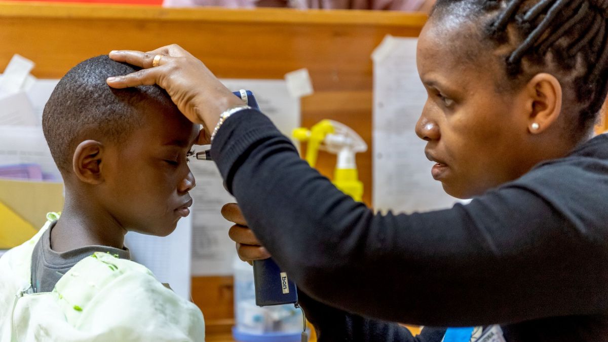 Eine Frau hält ein Untersuchungsgerät vor das Auge eines Kindes