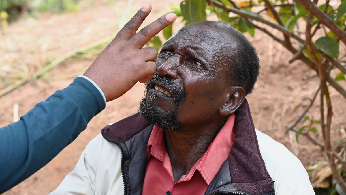Ein Mann schaut mit gerunzelter Stirn auf die zwei Finger, die ihm jemand vors Gesicht hält.