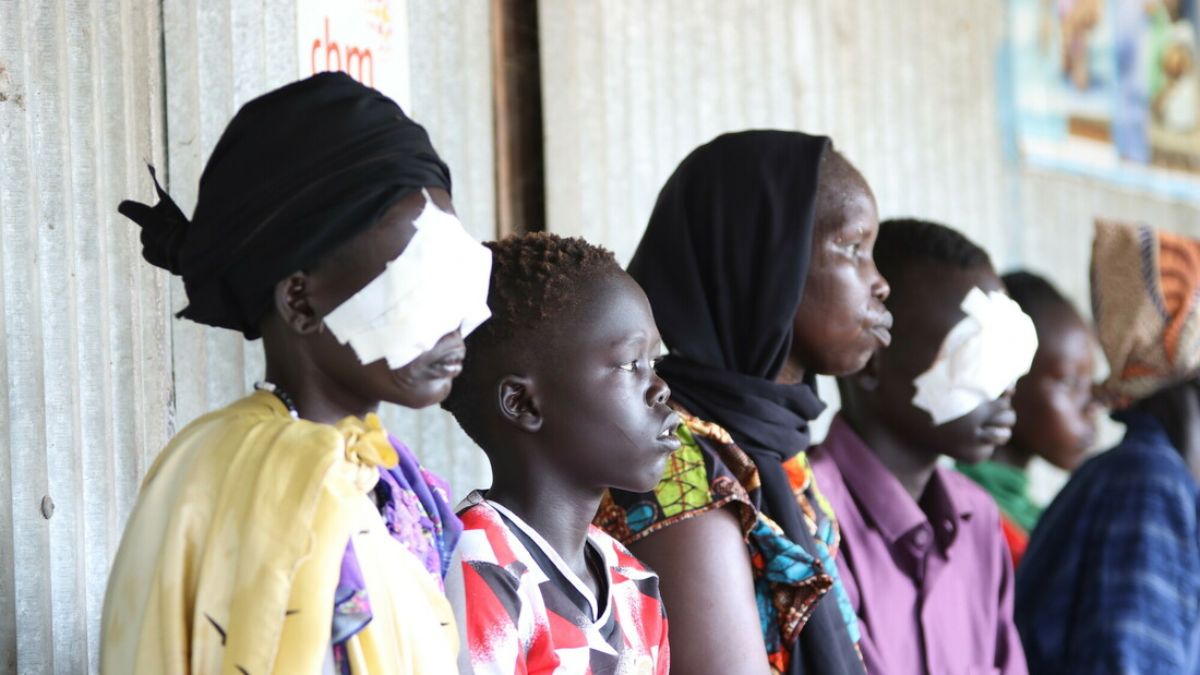 Mehrere Frauen sitzen nebeneinander. Zwei von ihnen haben die Augen verbunden.