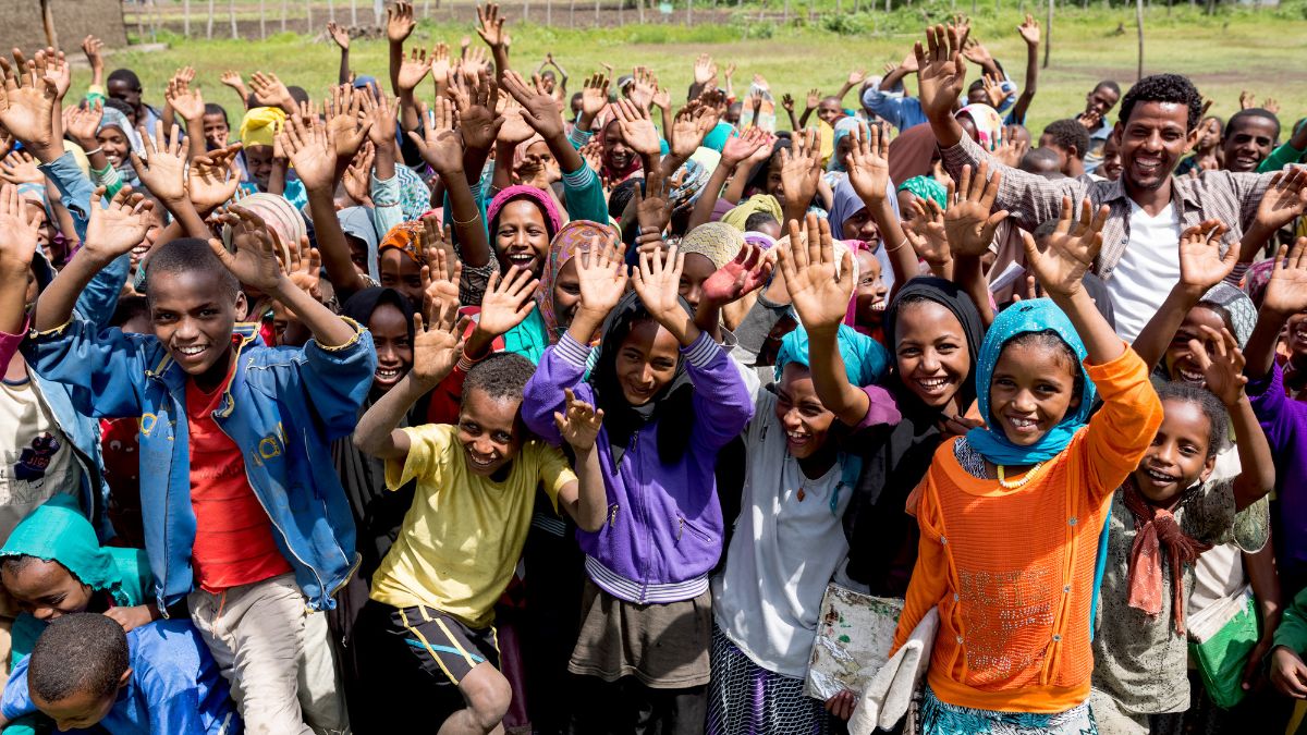 Eine Gruppe afrikanischer Kinder winkt mit erhobenen Händen.