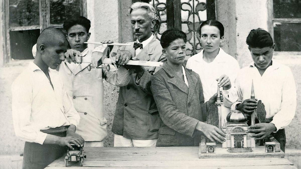 Ein Mann, eine Frau und einige Jugendliche betasten ein Flugzeugmodell und das Modell  eines Gebäudes