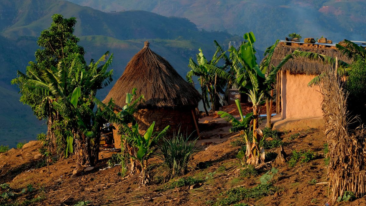 Hütten auf einem Hügel, hohe Berge im Hintergrund