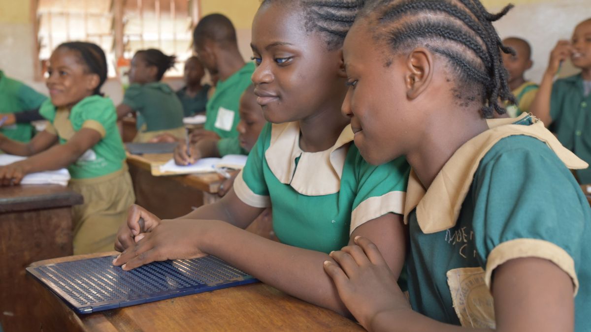 Zwei Mädchen mit einer Braille-Tafel in einer Unterrichtsklasse