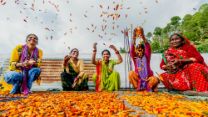 Fünf Frauen in bunten Saris sitzen auf dem Boden und werfen Chilis in die Luft.