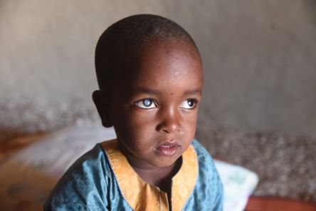 Kleiner Junge im bunten Kaftan mit auffällig weißen Pupillen