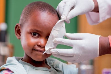Bei einem kleinen ruandischen Mädchen wird eine Augenklappe entfernt