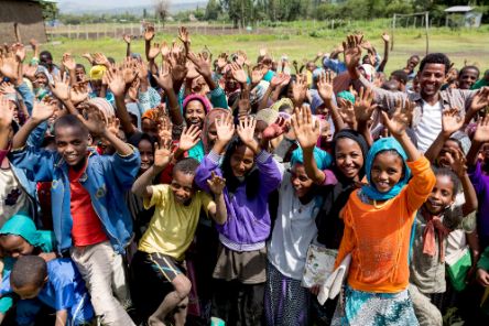 Eine Gruppe afrikanischer Kinder winkt mit erhobenen Händen.