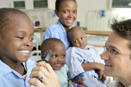 Ein Mann im weißen Kittel untersucht die Augen eines afrikanischen Mädchens
