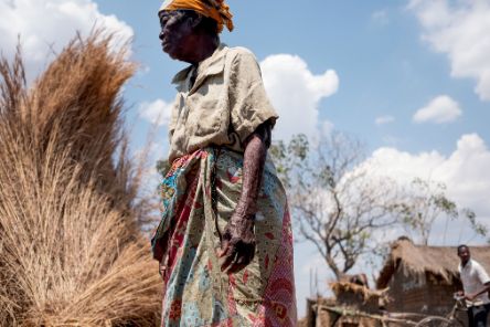 Eine alte Frau steht vor Bündeln von getrocknetem Gras