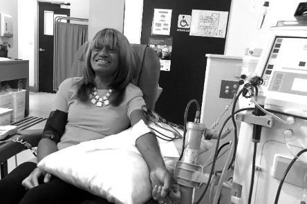 Eine lächelnde Frau bekommt eine Infusion.