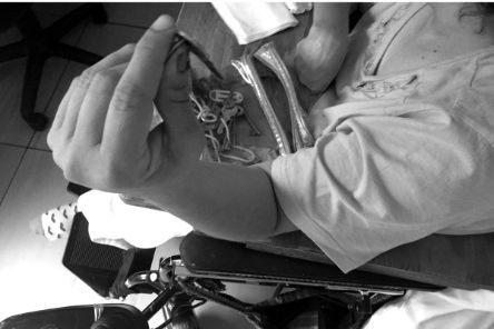 Eine Person im Rollstuhl stützt ihren Arm auf die Lehne und hält einen Schlüssel in der Hand. Auf dem Rollstuhltischchen liegen mehrere Schlüssel.