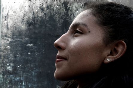 Lächelnde Frau im Profil vor einer Glasscheibe voller Wassertropfen