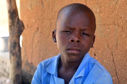 Etwa zehnjähriger Junge mit zusammengekniffenen Augen.