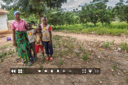 Eine Frau und zwei Kinder stehen vor einem kleinen Haus.
