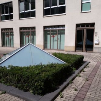 Mehrgeschossiges Bürogebäude, davor ein Beet.