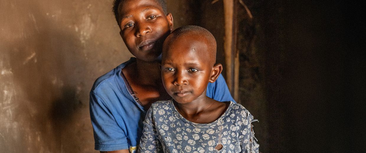 Ein kleines Mädchen mit auffallend hellen Pupillen und eine Frau in einem dunklen Raum.