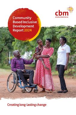 Ein Mann im Rollstuhl und eine Frau im weißen Polohemd mit CBM-Logo stehen rechts und links neben einer Frau, die einen etwa achtjährigen Jungen trägt. Alle lächeln.