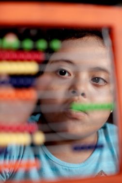 Mädchen mit dunklen Augen schaut konzentriert auf Rechenschieber.