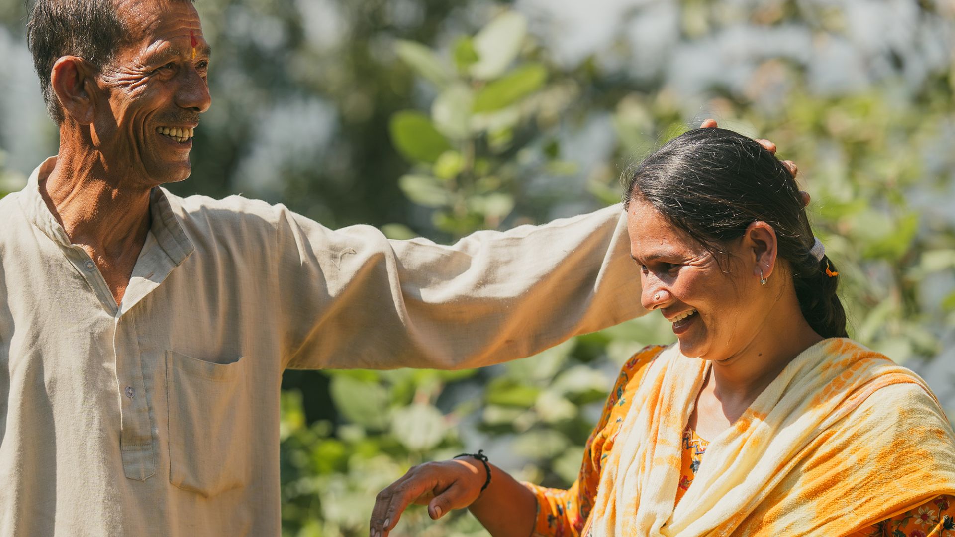 Ein Mann legt die Hand auf den Kopf einer Frau im Sari.