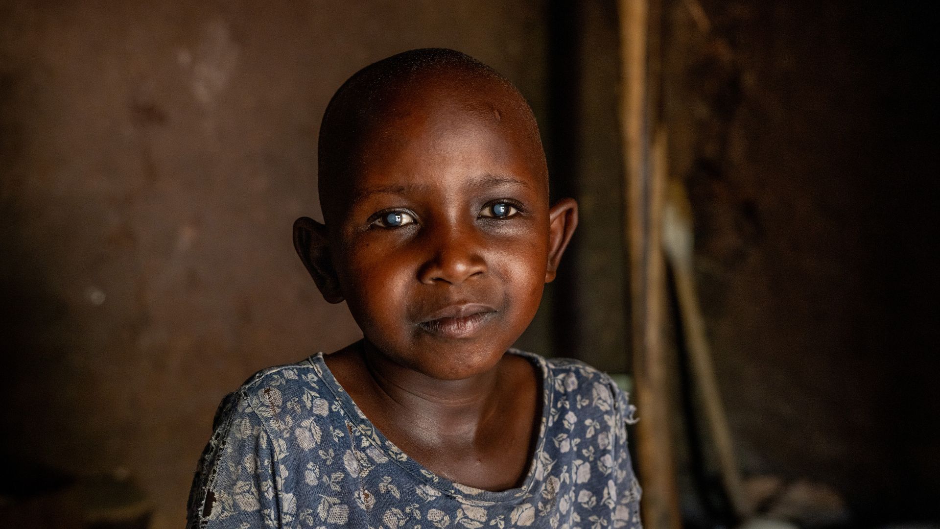 Ein kleines Mädchen mit auffallend hellen Pupillen in einem dunklen Raum.