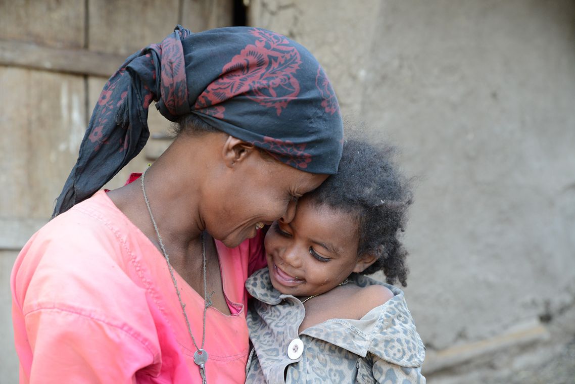 Momina sitzt auf den Schoß ihrer Mutter. Sie lächeln sich an.