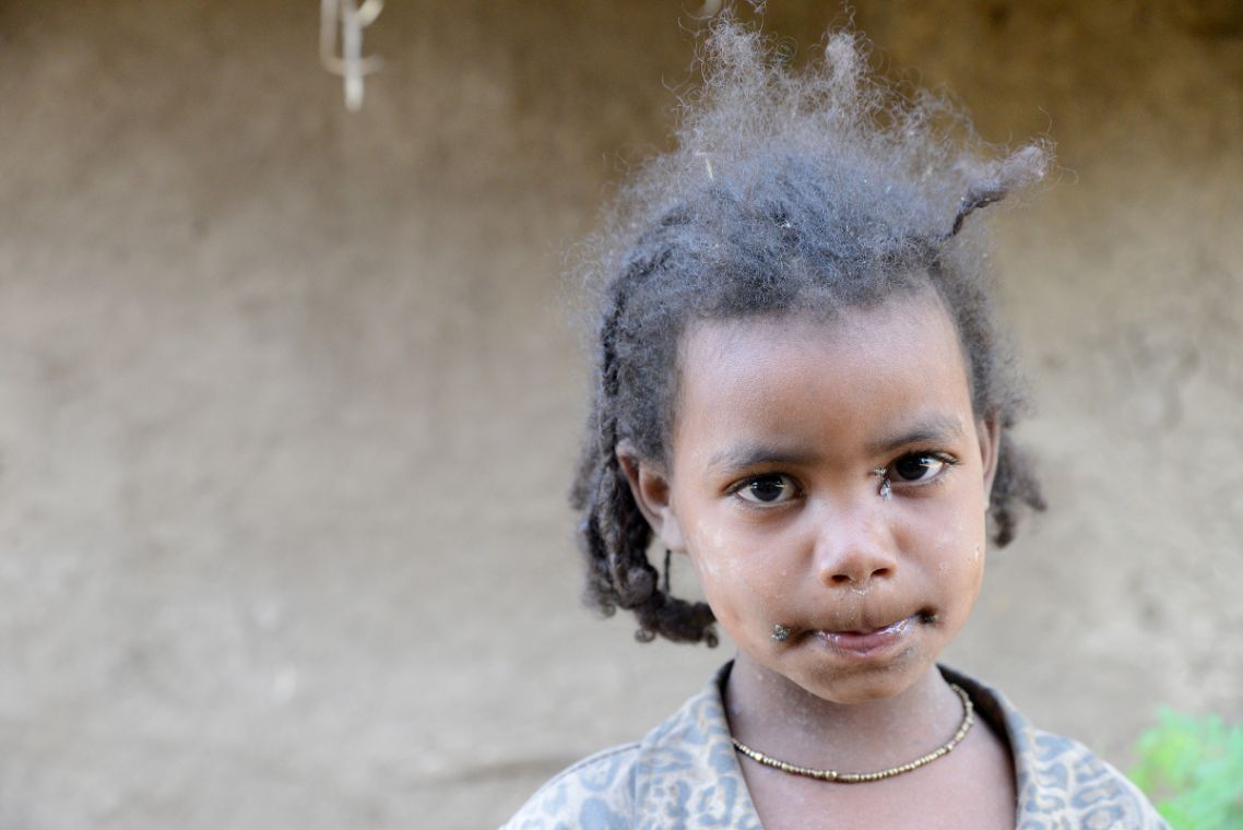 Afrikanisches Mädchen vor einer Lehmwand
