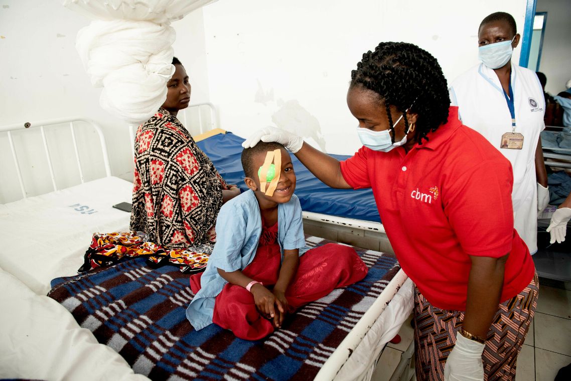 Eine Frau entfernt den Augenverband eines Kindes.