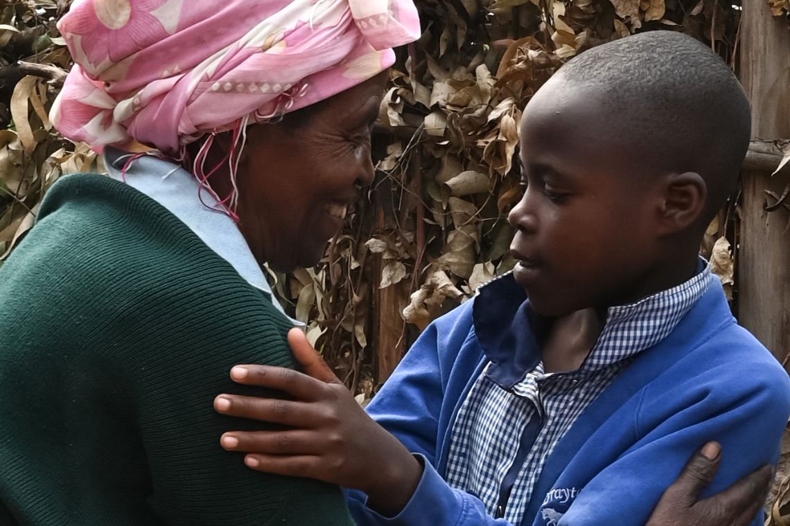 Ein Mädchen und eine alte Frau umarmen sich zur Begrüßung.