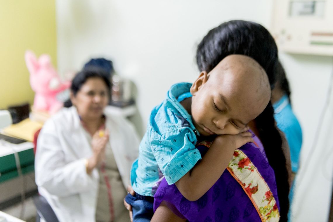 Schlafendes Kleinkind auf der Schulter einer Frau im Sari