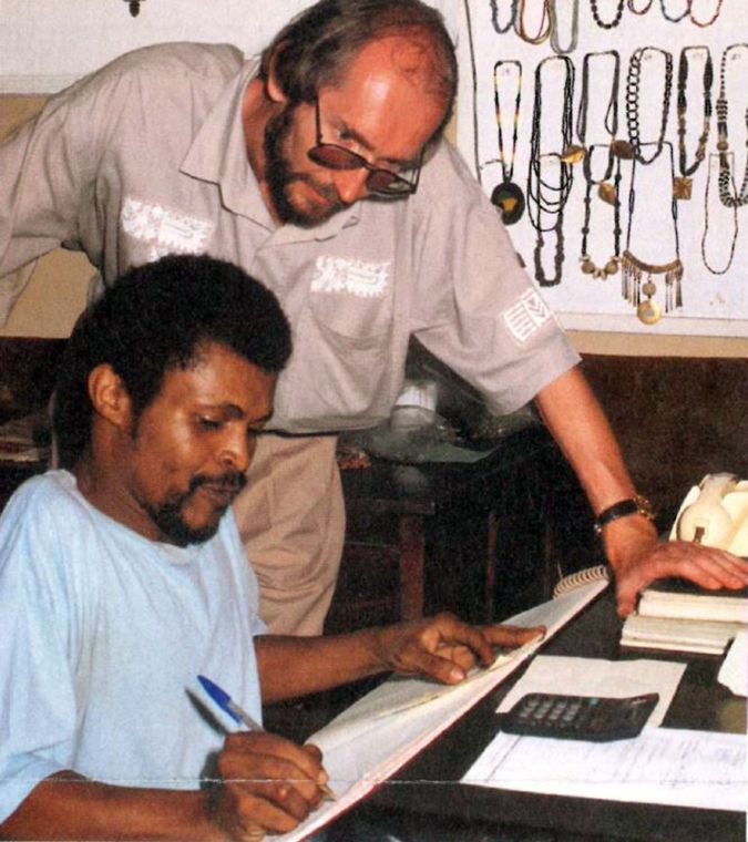 Ein stehender und ein sitzender Mann schauen in ein aufgeschlagenes Heft.