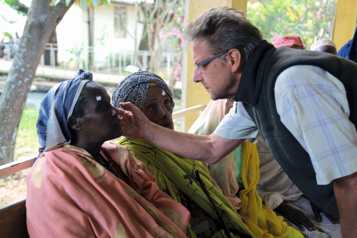 Ein Mann untersucht die Augen einer Frau.