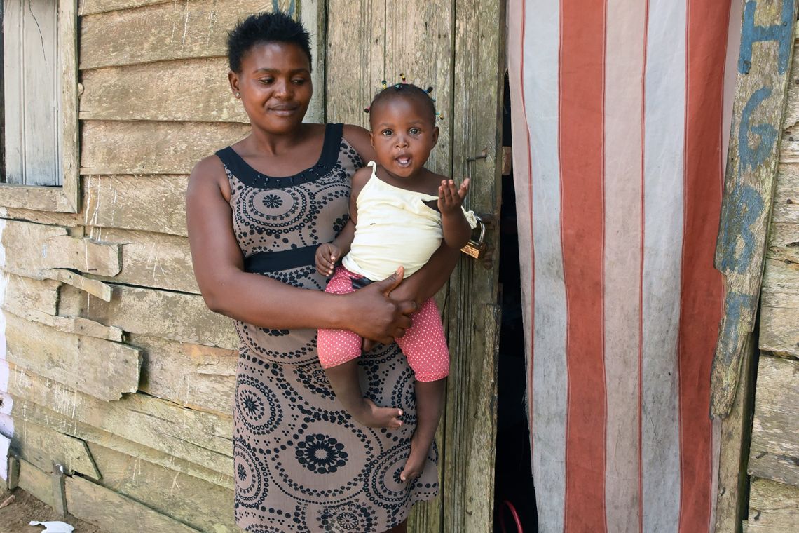 Eine Frau hält ein Kleinkind mit gekrümmtem Fuß und Bein auf dem Arm