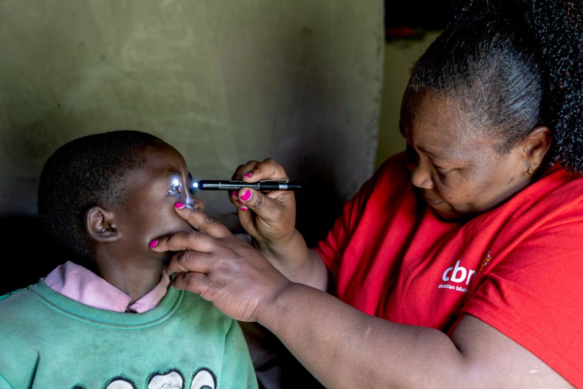 Eine Frau leuchtet mit einer kleinen Lampe in die Augen eines Mädchens.