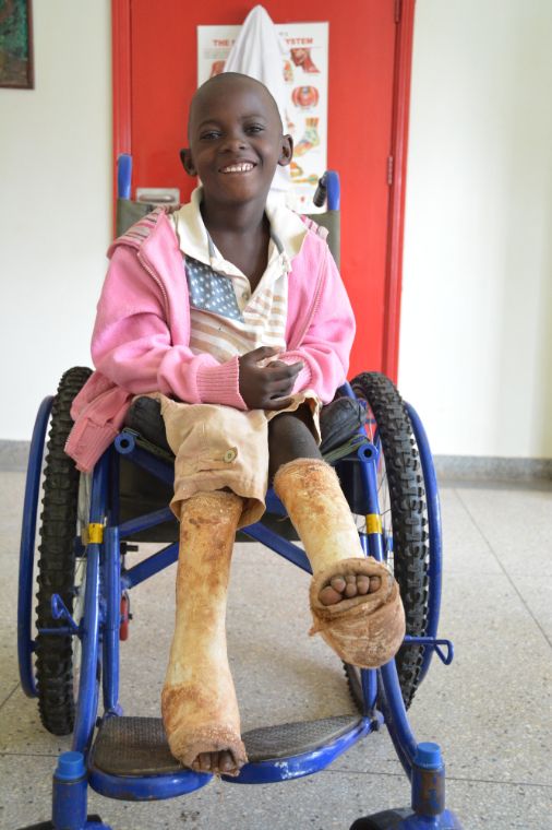 Lachender Junge mit braun gewordenen Gipsbeinen im Rollstuhl