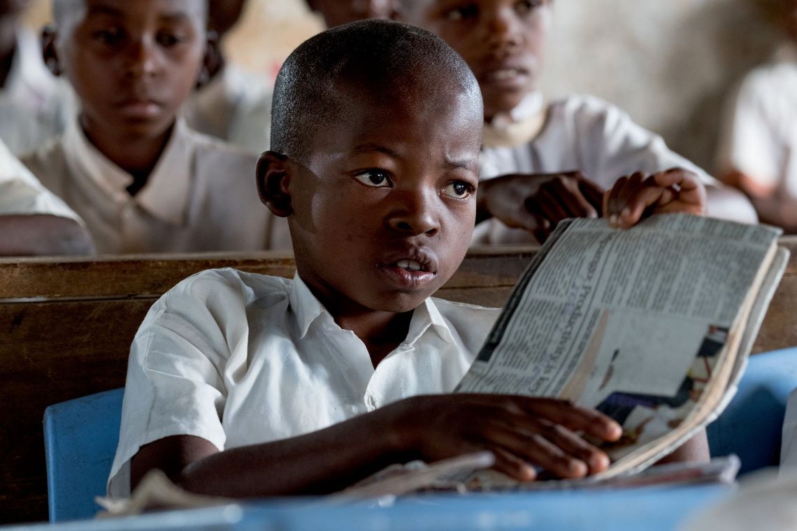Eine junge Frau im weißen Kittel. Ihr Haar ist zu Zöpfchen geflochten und hochgesteckt.