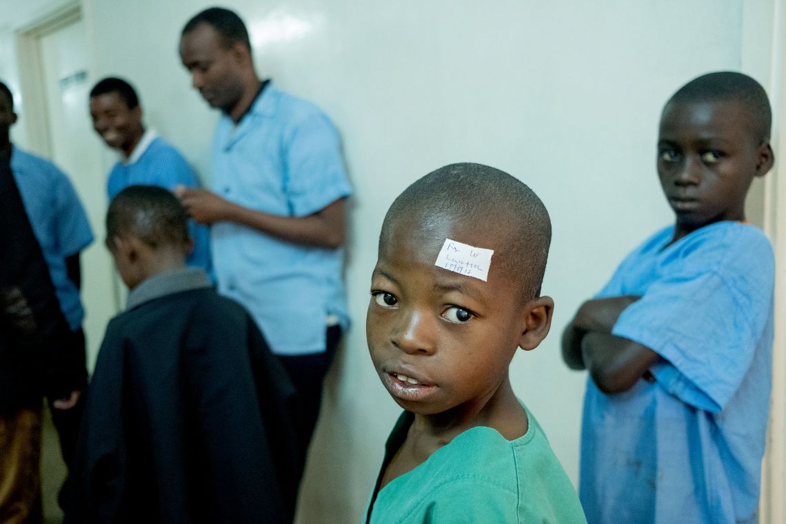 Ein junge im OP-Kittel und einem Pflaster über dem linken Auge.