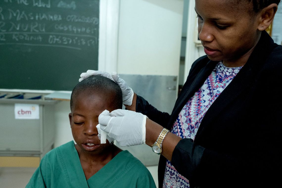 Eine junge Frau im weißen Kittel. Ihr Haar ist zu Zöpfchen geflochten und hochgesteckt.