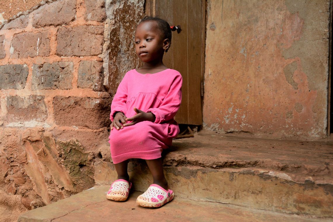 Afrikanisches Mädchen sitzt vor einer Hütte