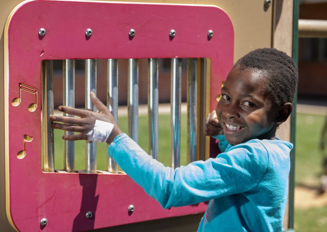 Ein etwa zehnjähriges Mädchen streift mit der Hand über die in einem Holzrahmen eingefassten Metallröhren.