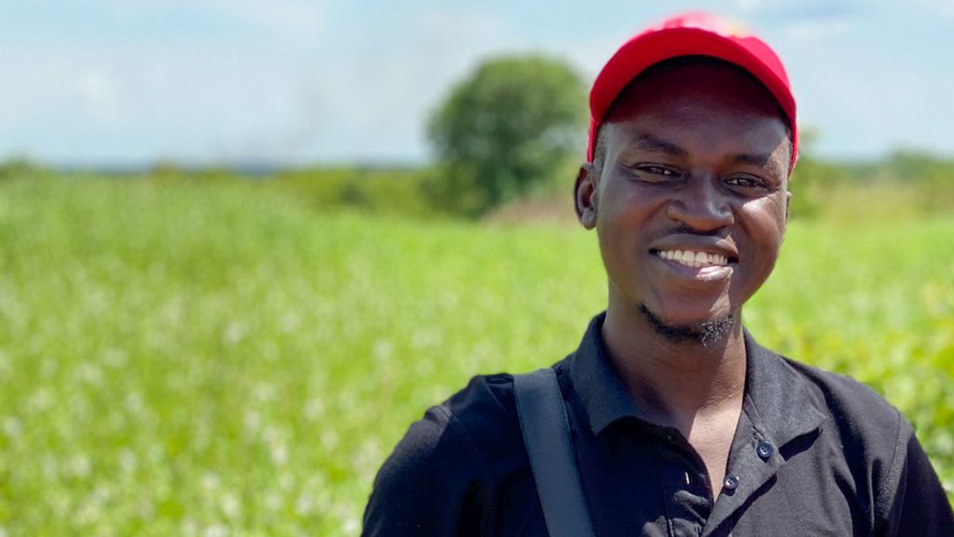 Zwei junge lachende afrikanische Männer, im Hintergrund ein Feld