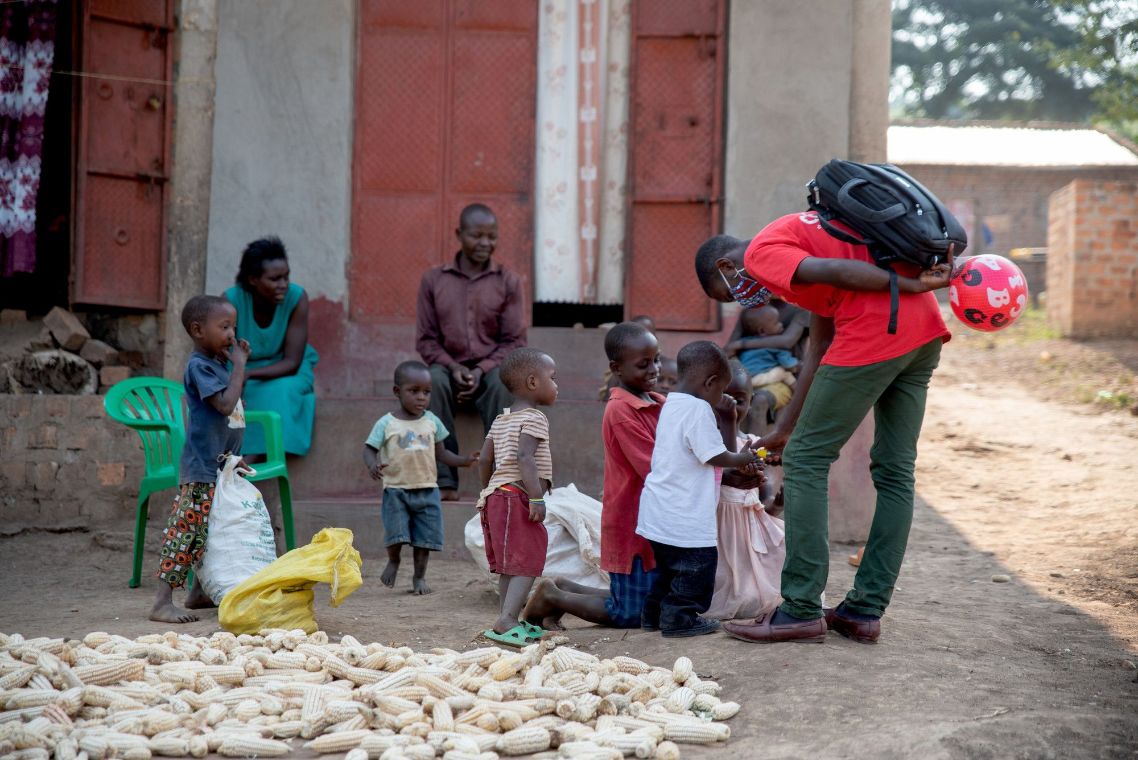 Drei junge lachende afrikanische Männer, im Hintergrund ein Feld