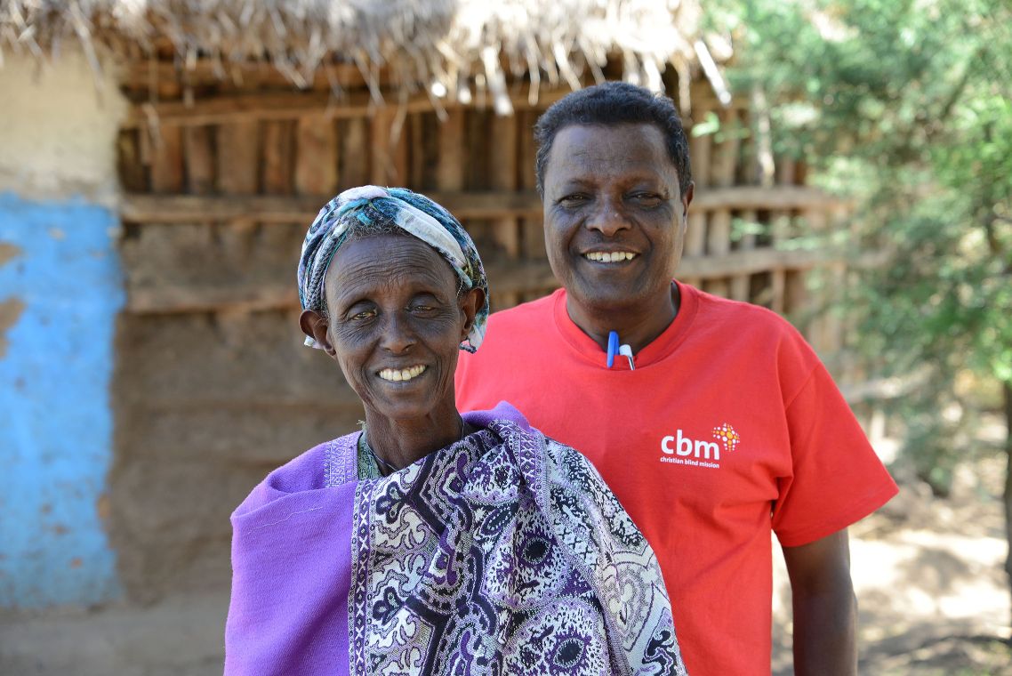 CBM-Mitarbeiter und Patientin stehen lächelnd nebeneinander