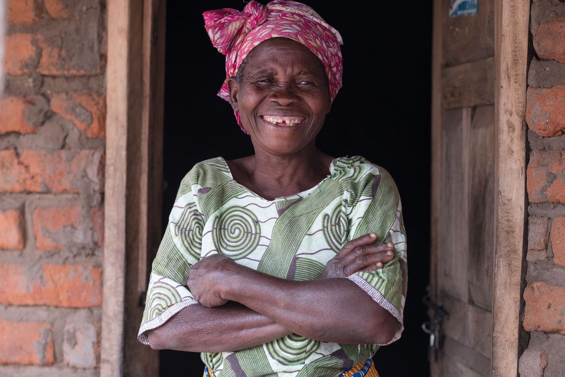 Frau steht lächelnd im Eingang ihres Hauses