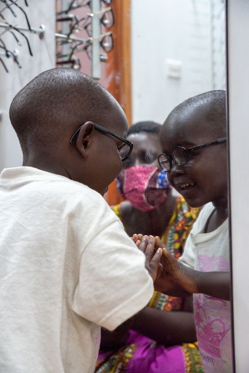 Kleiner Junge mit Brille betrachtet sich selbst im Spiegel.