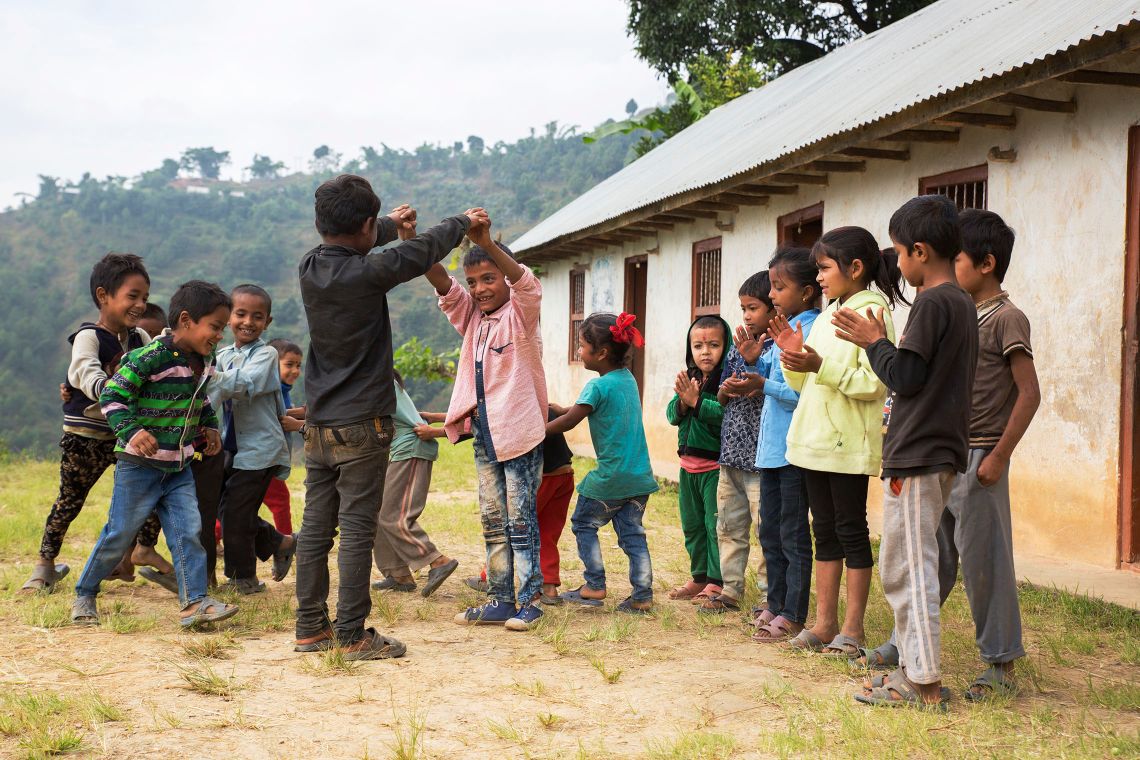 Kinder spielen vor dem Schulgebäude miteinander.