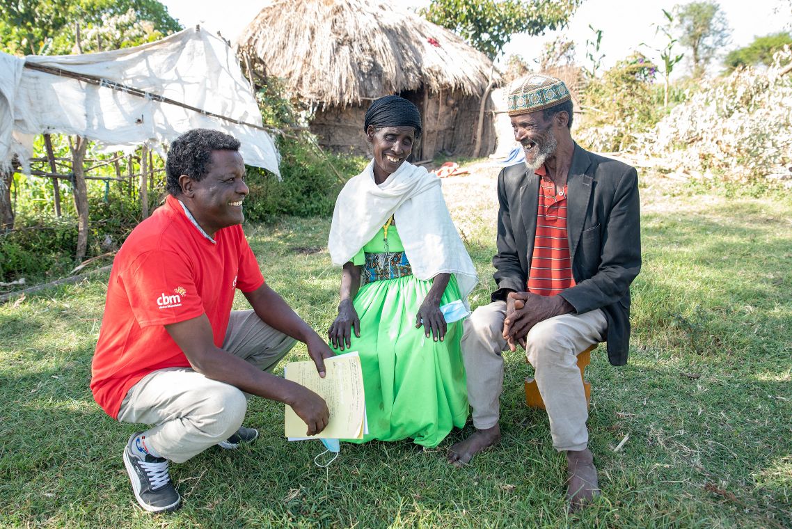 Ein Mann mit rotem T-Shirt spricht mit einem Ehepaar.