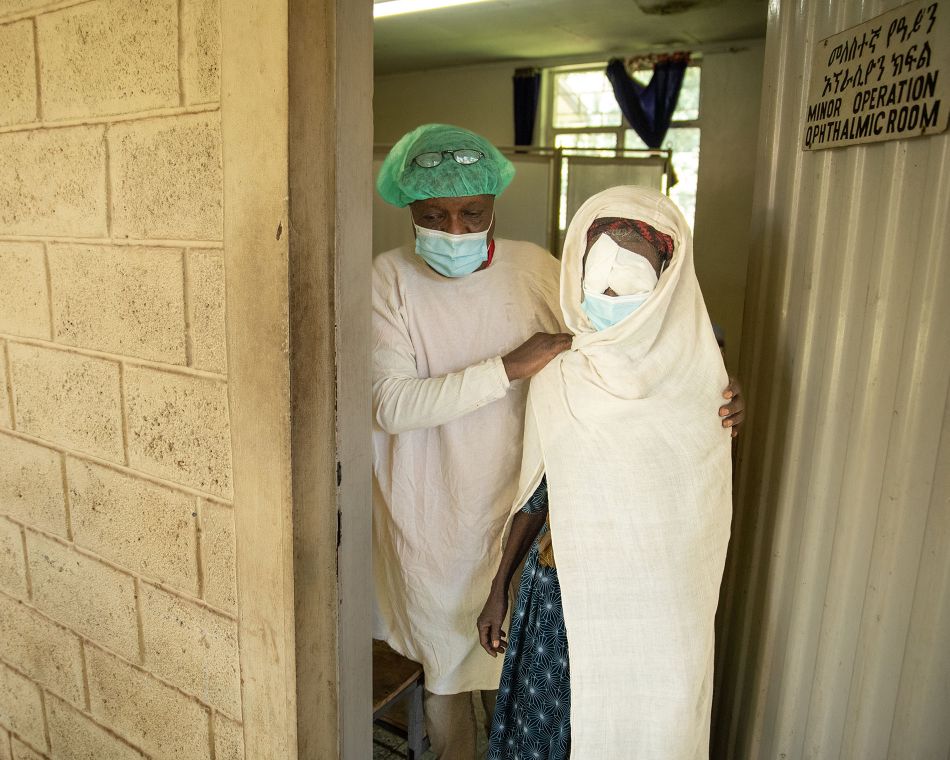 Ein Ehemann begleitet seine Frau nach einer Augen-OP aus dem OP-Saal heraus.