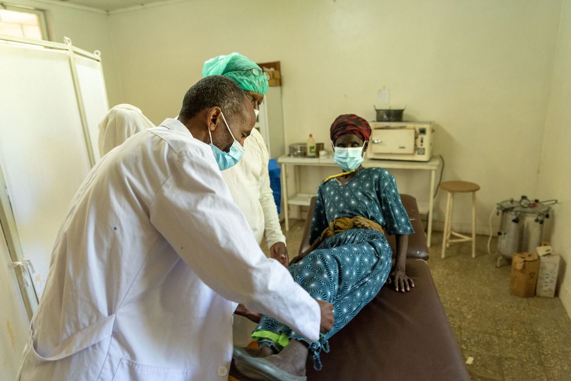 Eine Frau legt sich in einem OP-Raum auf einen OP-Tisch.